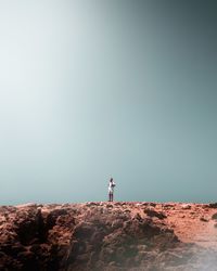 Man standing on rock against sky