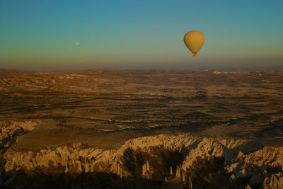 Hot air balloon flying over cappadocia against clear sky during sunset