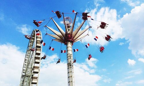 Low angle view of ferris wheel against cloudy sky