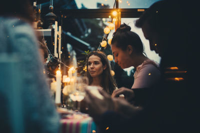 Multi-ethnic young friends sitting in conservatory during dinner party