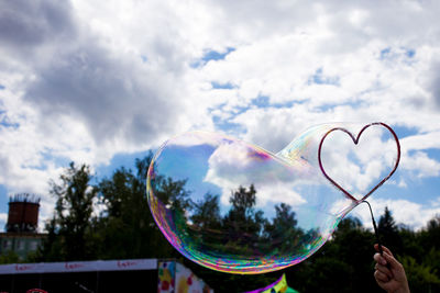Close-up of person making bubble against sky