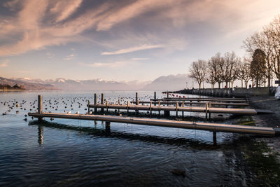 Pier over lake against sky during sunset