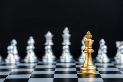 Close-up of chess pieces on board against black background