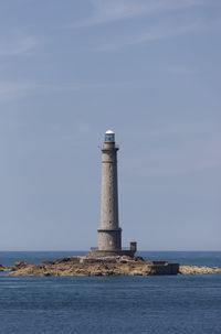 Lighthouse by sea against sky