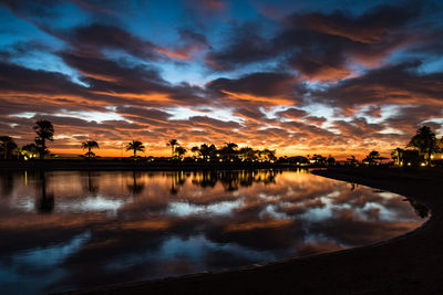 Scenic view of lake against dramatic sky during sunset