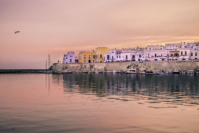 Reflection of building in sea at sunset