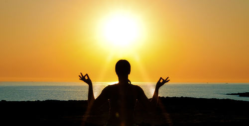 Silhouette man on beach against sky during sunset