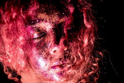 Close-up portrait of a beautiful young woman over black background
