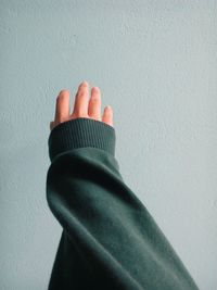 Close-up of cropped hand reaching towards wall at home