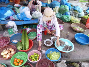 High angle view of vendor cleaning prawns while sitting at market stall