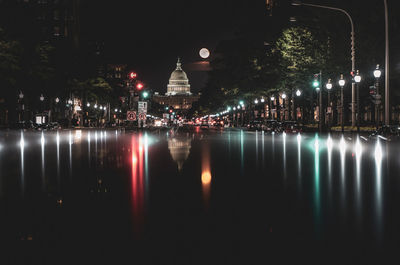 Illuminated street lights reflecting on lake at night