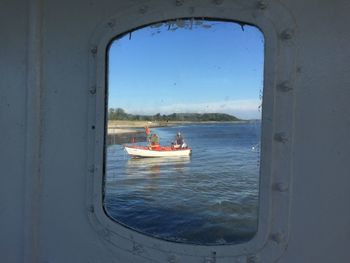 Man in boat on sea seen through window