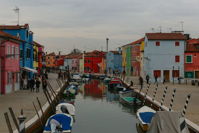 Boats in canal amidst buildings in city against sky