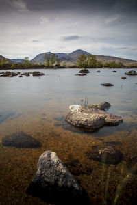 Rocks in lake against sky