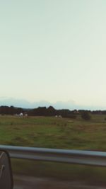 Road by field against clear sky