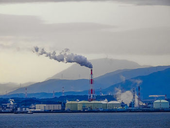 Smoke emitting from factory against sky