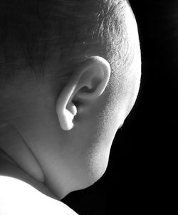 Side view of baby girl sitting against black background