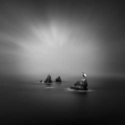 Scenic view of rocks in sea against sky