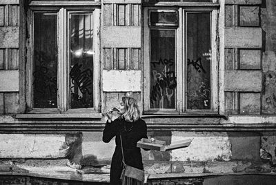 Woman standing by window of building