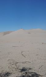 Scenic view of sand dunes against clear blue sky