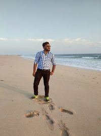 Full length of boy standing on beach against sky