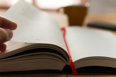 Cropped hand of person writing in open book