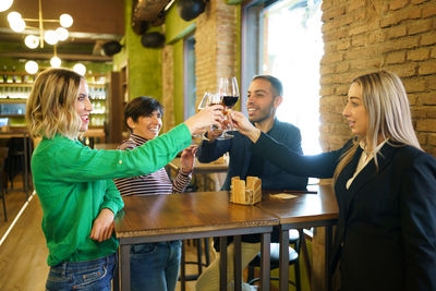 Happy friends toasting wines at bar