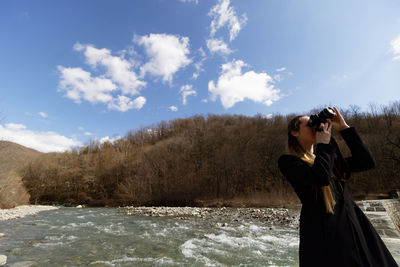 Woman photographing against sky