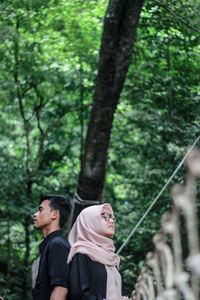 Side view of young couple looking away in forest