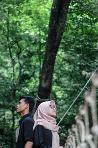 Couple standing back to back in forest