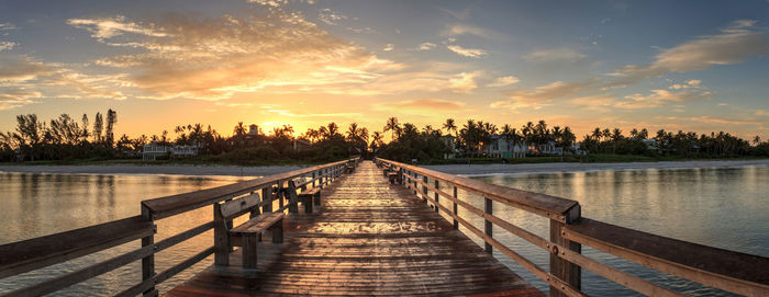 Pier over lake against sky during sunset