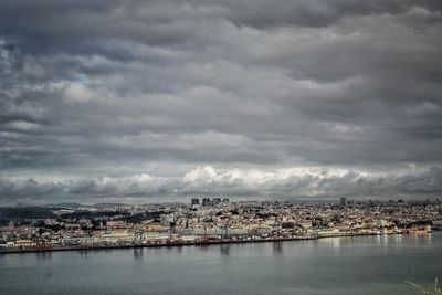 Aerial view of city by sea against storm clouds
