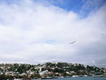 Airplane flying over city against sky