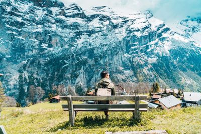 Rear view of man sitting on bench against plants