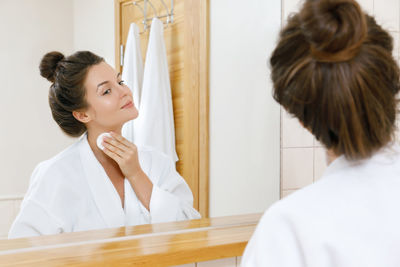 Woman applying moisturizer at home