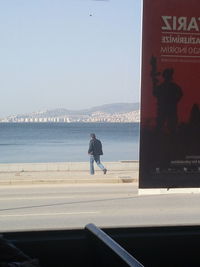 Man walking on beach against clear sky