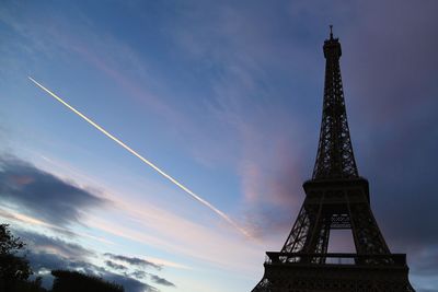 Low angle view of eiffel tower against vapor trail in sky