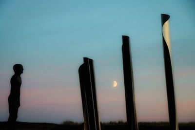 Low angle view of silhouette person against moon at sunset