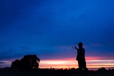 Silhouette of people standing on field at sunset