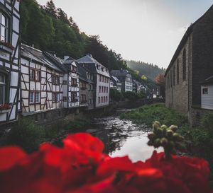 Houses by river and buildings against sky