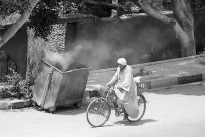 Rear view of man cycling on road in city