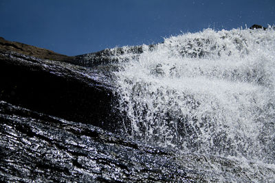 Waves splashing on shore against clear sky