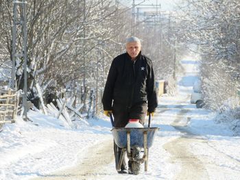 Man with wheelbarrow on road during winter