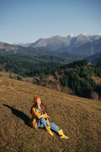 Side view of woman sitting on mountain