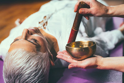 Cropped hands of woman playing singing bowl for customer in spa