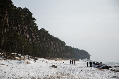 People at beach against sky during winter
