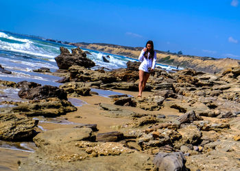 Tilt shot of woman walking on shore at beach against sky