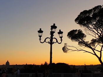Silhouette street light and buildings against sky during sunset
