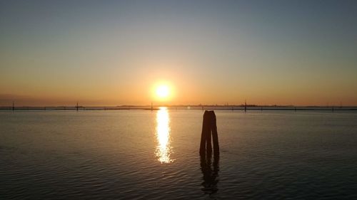 Silhouette people on sea against sky during sunset