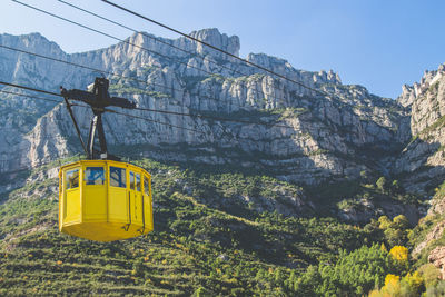 Low angle view of overhead cable car against rocky mountains at montserrat